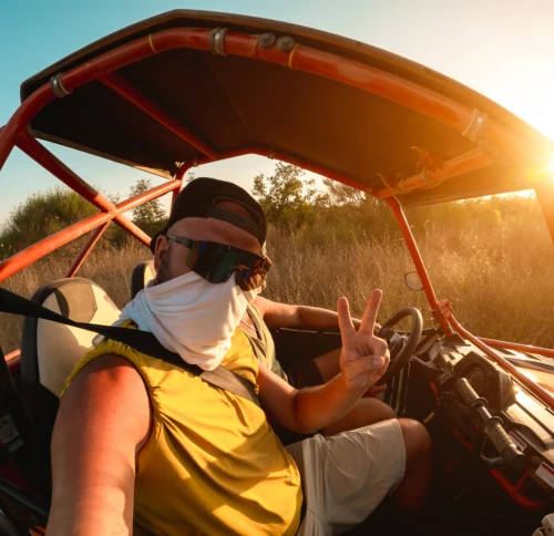 tourist taking selfie while driving off road buggy in desert safari