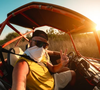 tourist taking selfie while driving off road buggy in desert safari