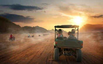 tourists riding desert buggy during sunset adventure in sand dunes