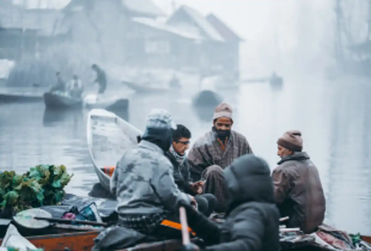 Local people rowing shikara boats on misty Kashmir lake