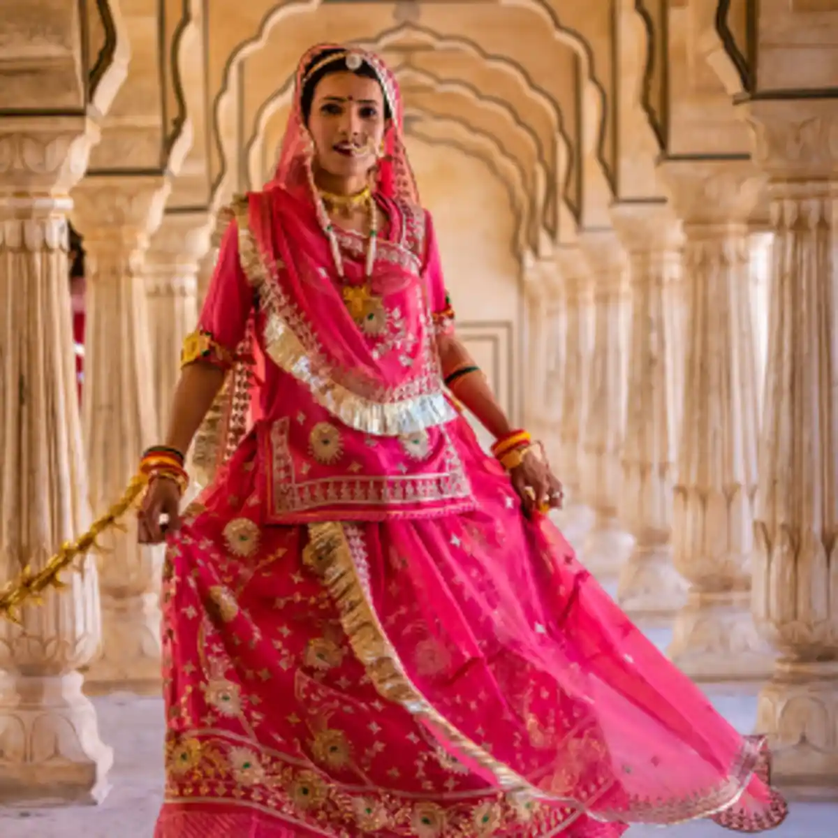 Rajasthani bride in traditional pink attire in palace corridor