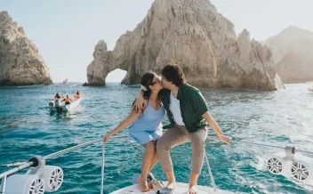 Couple kissing on yacht with rock arch formation in background