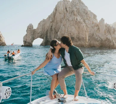 Couple kissing on yacht with rock arch formation in background