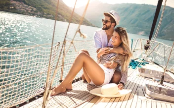 Happy couple relaxing on sailboat deck during sunny summer holiday