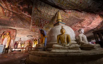 Golden Buddha statues inside Dambulla Cave Temple with painted ceiling
