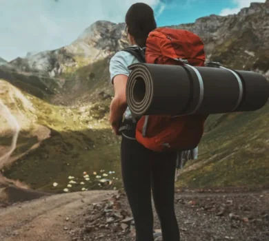 Female hiker with red backpack trekking in mountain landscape