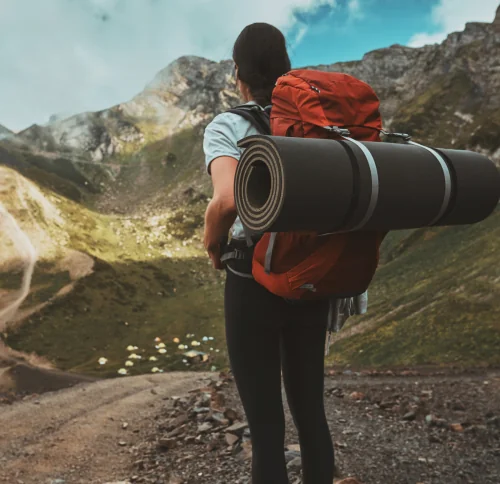 Female hiker with red backpack trekking in mountain landscape