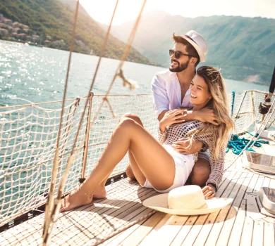 Happy couple relaxing on sailboat deck during sunny summer holiday